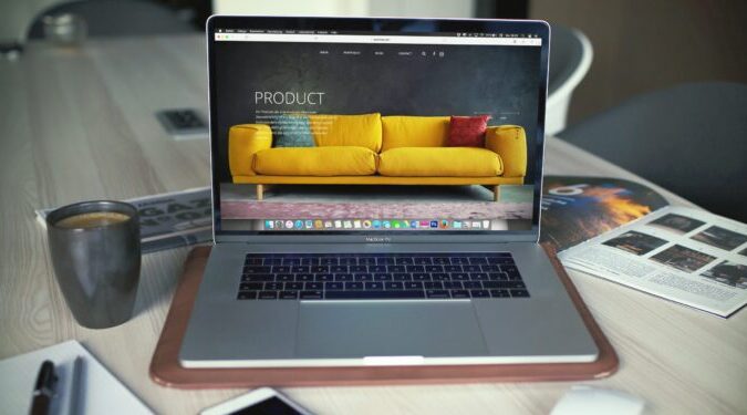 Laptop computer sitting on a desk with iPhone and mouse.